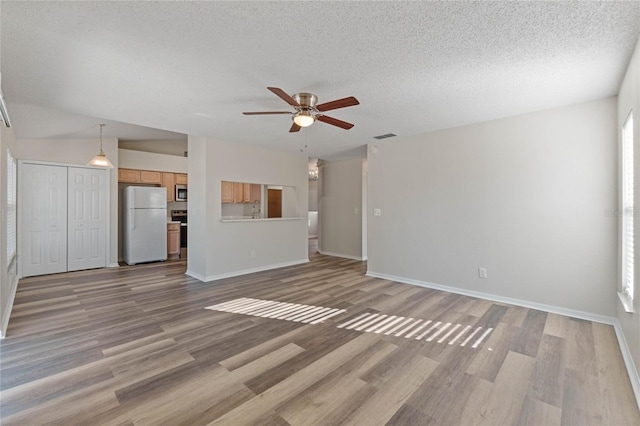 unfurnished living room featuring a textured ceiling, light hardwood / wood-style floors, plenty of natural light, and ceiling fan