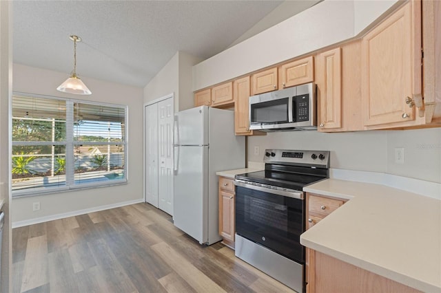 kitchen with hanging light fixtures, stainless steel appliances, light hardwood / wood-style flooring, vaulted ceiling, and light brown cabinetry