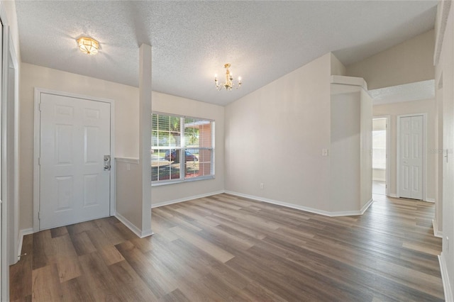 entrance foyer featuring an inviting chandelier, wood-type flooring, a textured ceiling, and vaulted ceiling