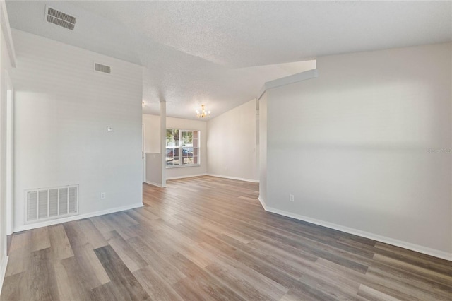 unfurnished living room with wood-type flooring, a textured ceiling, and a chandelier