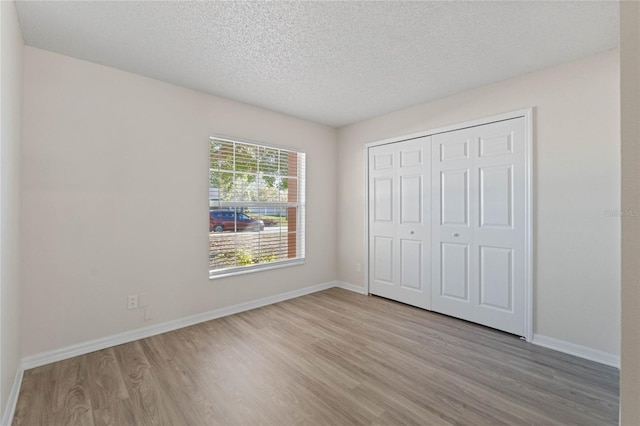 unfurnished bedroom with a closet, a textured ceiling, and light hardwood / wood-style flooring