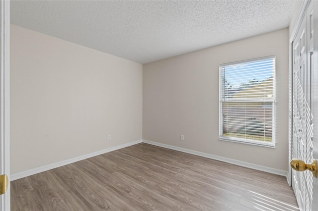 spare room with light hardwood / wood-style floors and a textured ceiling