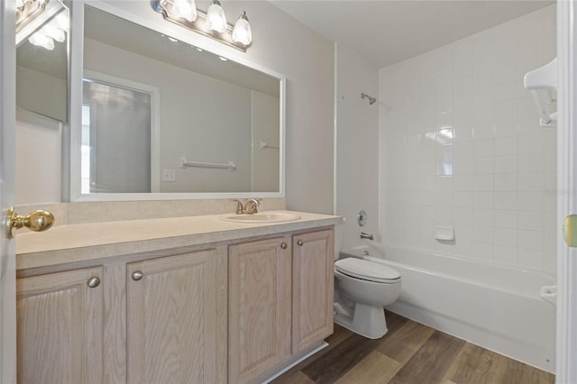 full bathroom with hardwood / wood-style floors, tiled shower / bath combo, toilet, and vanity