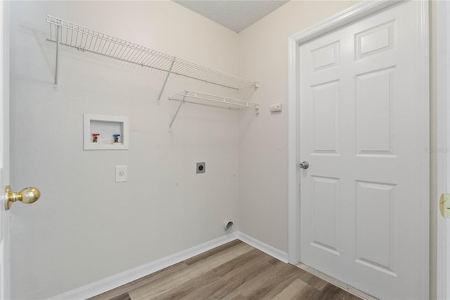 laundry area featuring electric dryer hookup, hookup for a washing machine, light hardwood / wood-style flooring, and a textured ceiling