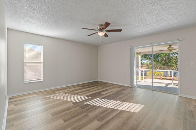 unfurnished room with a textured ceiling, hardwood / wood-style flooring, and a wealth of natural light