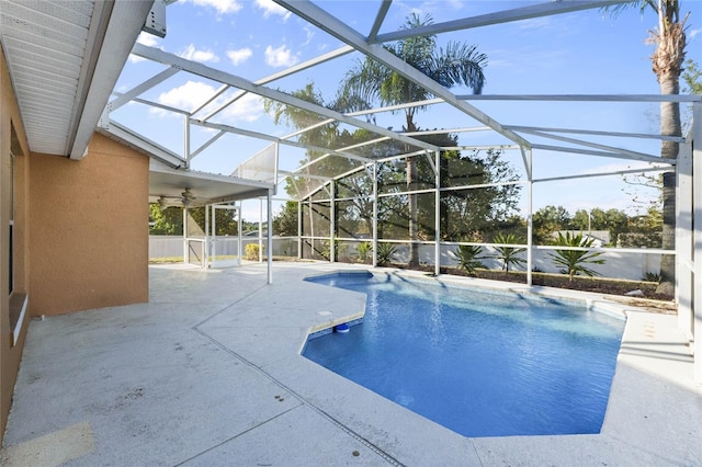 view of swimming pool featuring glass enclosure, ceiling fan, and a patio