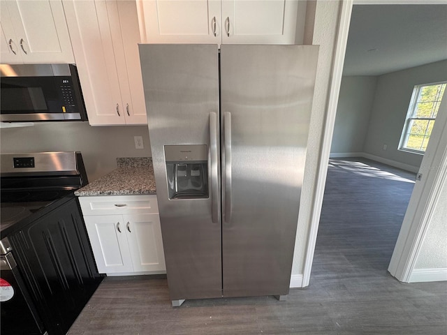 kitchen with dark wood-type flooring, stainless steel appliances, light stone counters, white cabinets, and washer / clothes dryer