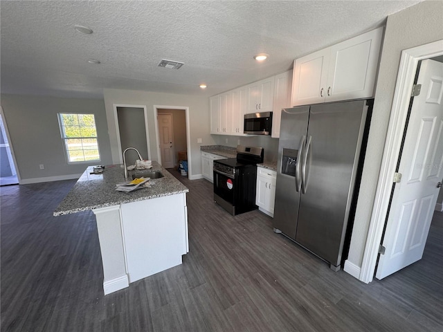 kitchen with white cabinetry, sink, dark hardwood / wood-style flooring, stainless steel appliances, and a center island with sink