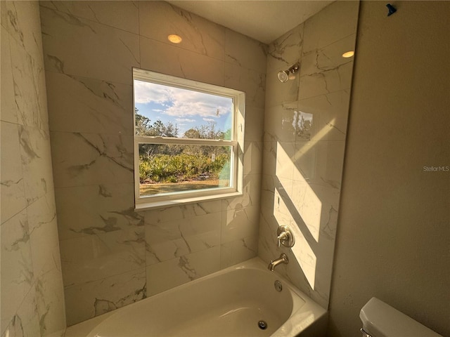 bathroom with toilet and tiled shower / bath combo