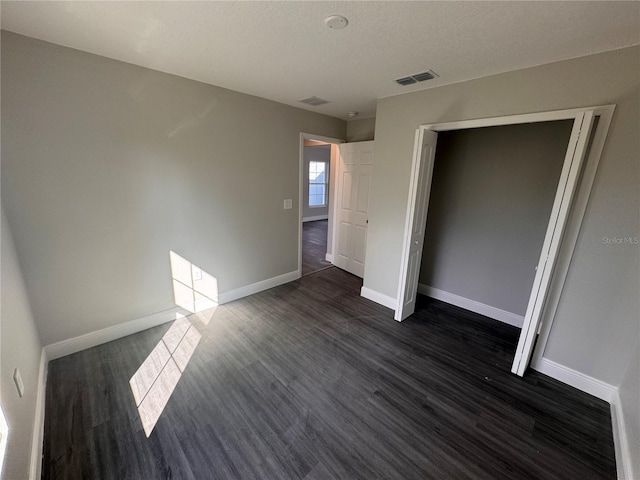 unfurnished bedroom featuring dark wood-type flooring and a closet