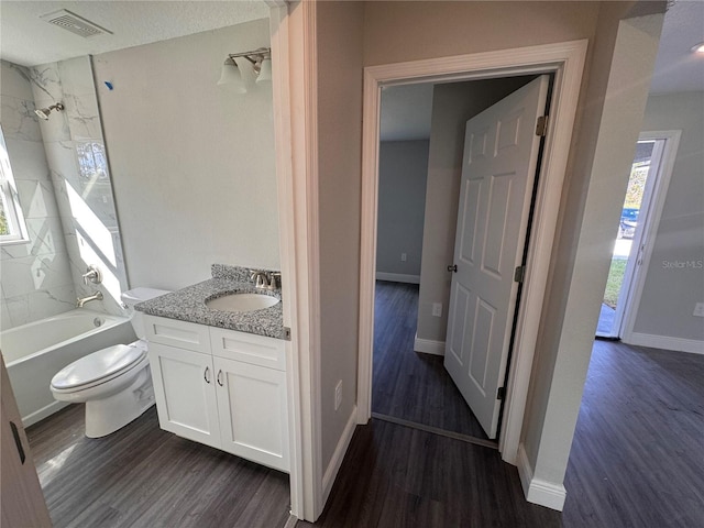 full bathroom with vanity, tiled shower / bath, wood-type flooring, and toilet