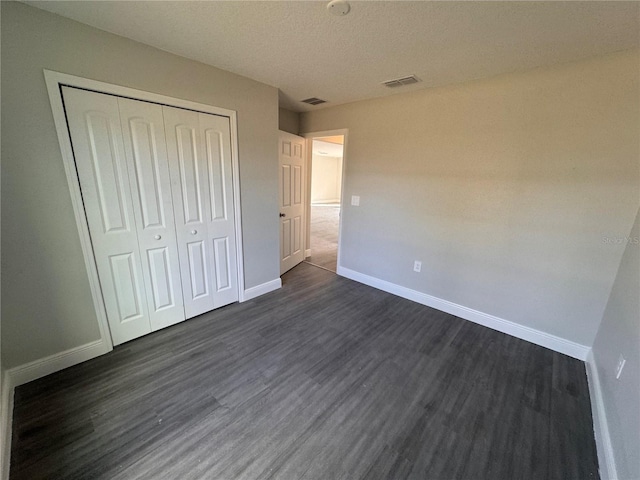 unfurnished bedroom with dark hardwood / wood-style flooring, a closet, and a textured ceiling