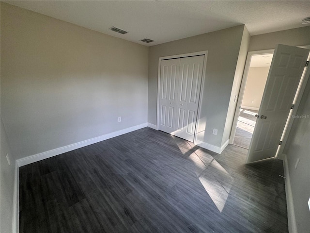 unfurnished bedroom with dark hardwood / wood-style flooring and a closet