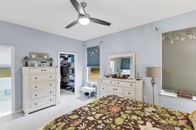 bedroom with ceiling fan, light colored carpet, a spacious closet, and a closet