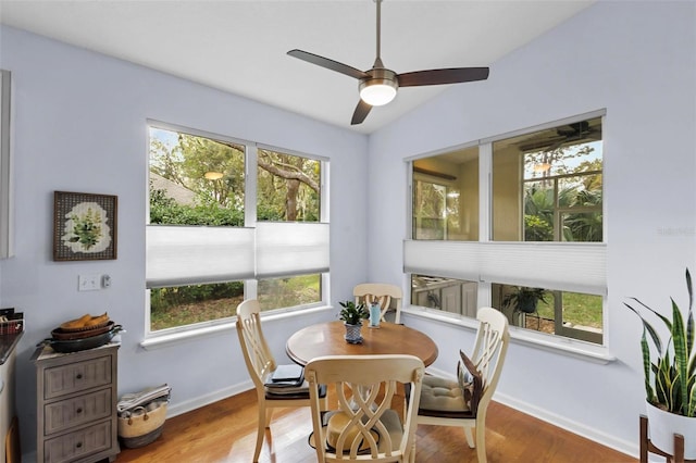 dining room with plenty of natural light, wood-type flooring, and vaulted ceiling