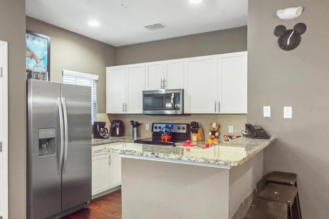 kitchen featuring white cabinets, kitchen peninsula, a breakfast bar area, and appliances with stainless steel finishes