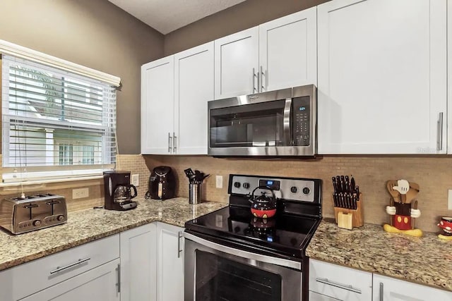 kitchen featuring decorative backsplash, light stone countertops, white cabinets, and stainless steel appliances