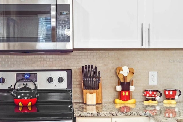 details with white cabinets, black stove, and light stone countertops