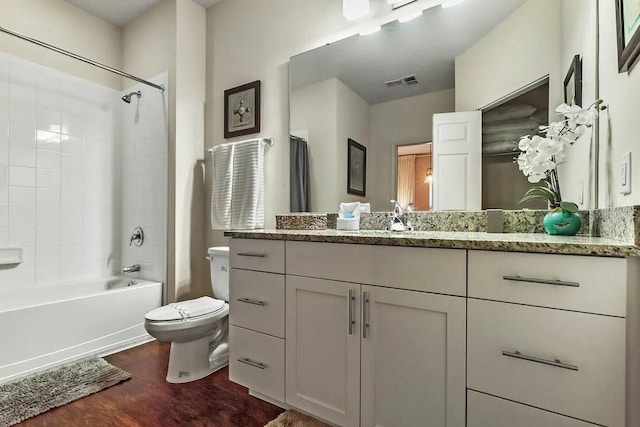 full bathroom with hardwood / wood-style floors, vanity, toilet, and tiled shower / bath