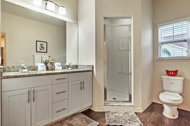 bathroom featuring vanity, hardwood / wood-style flooring, toilet, and a shower with shower door