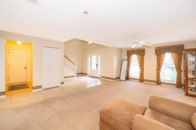 unfurnished living room with ceiling fan, light colored carpet, and a textured ceiling