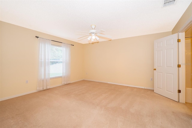 spare room featuring light carpet, ceiling fan, and a textured ceiling