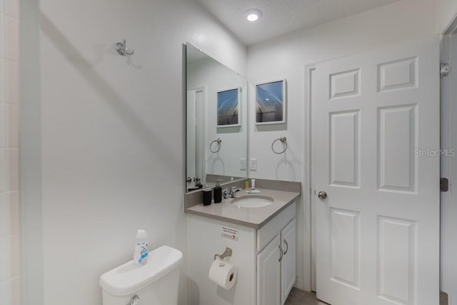 bathroom featuring vanity, a textured ceiling, and toilet