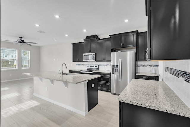 kitchen with ceiling fan, sink, tasteful backsplash, a kitchen island with sink, and appliances with stainless steel finishes