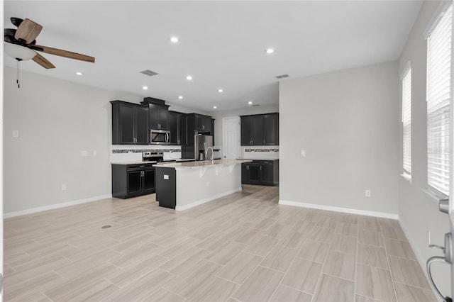 kitchen featuring appliances with stainless steel finishes, sink, a kitchen island with sink, and a wealth of natural light