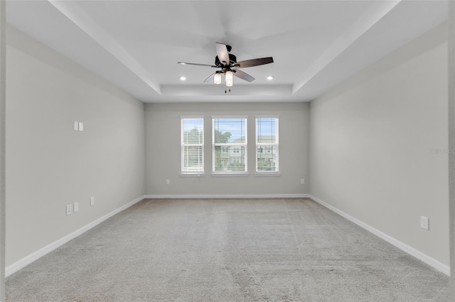 carpeted spare room featuring ceiling fan and a raised ceiling