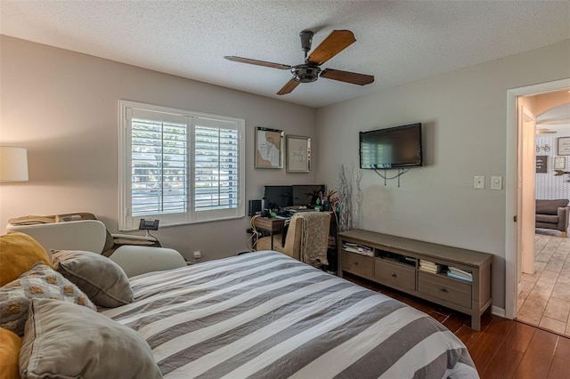 bedroom featuring a textured ceiling, dark hardwood / wood-style floors, and ceiling fan