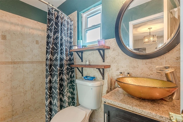 bathroom featuring vanity, toilet, walk in shower, and tile walls