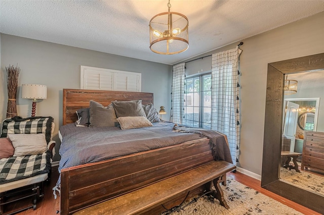 bedroom with a textured ceiling, a chandelier, and dark hardwood / wood-style floors