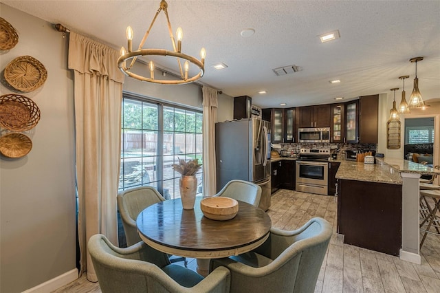 dining area with a chandelier, light hardwood / wood-style floors, and a textured ceiling