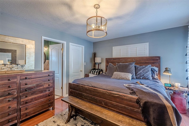 bedroom featuring a chandelier, a textured ceiling, and light hardwood / wood-style floors