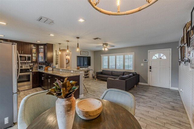 dining space featuring ceiling fan, a textured ceiling, and light wood-type flooring