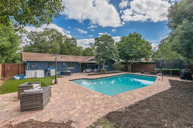 view of swimming pool featuring a jacuzzi, a trampoline, and a patio area