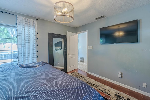 bedroom with access to outside, an inviting chandelier, a textured ceiling, and hardwood / wood-style flooring