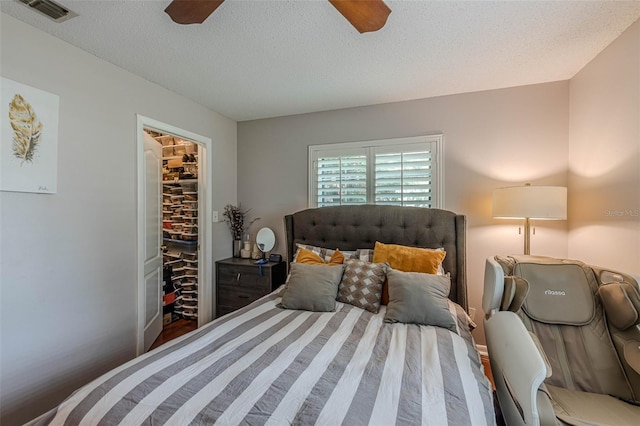 bedroom featuring a textured ceiling, a spacious closet, a closet, and ceiling fan