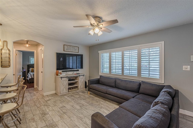 living room with a textured ceiling, light hardwood / wood-style floors, and ceiling fan