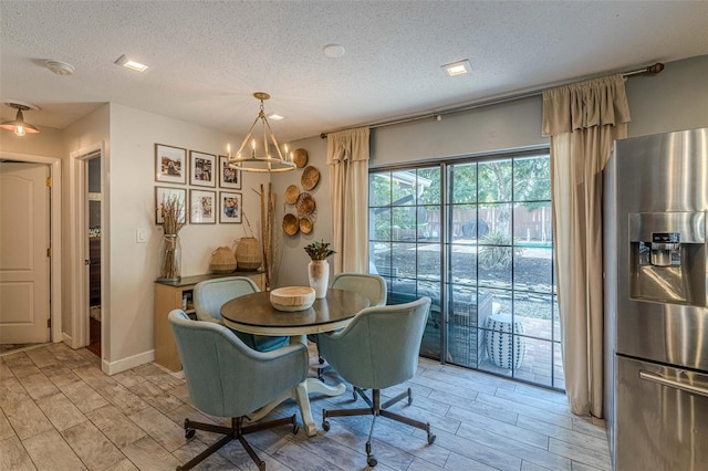 dining room with light hardwood / wood-style floors, a textured ceiling, and a chandelier