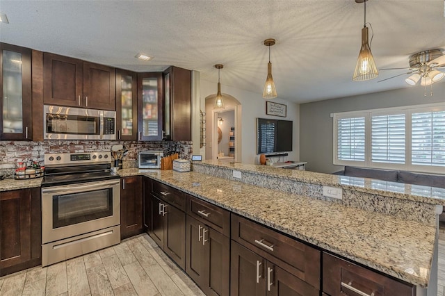 kitchen featuring tasteful backsplash, stainless steel appliances, a peninsula, dark brown cabinets, and ceiling fan