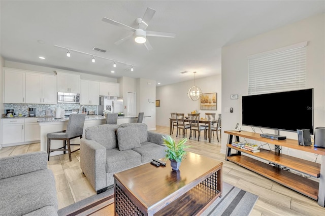 living room with light hardwood / wood-style floors and ceiling fan with notable chandelier