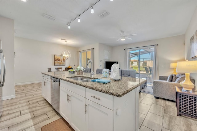 kitchen with light stone countertops, stainless steel dishwasher, sink, white cabinetry, and an island with sink