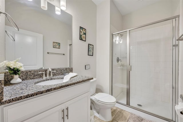 bathroom featuring vanity, toilet, a shower with shower door, and wood-type flooring