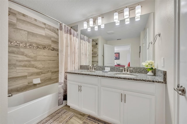 bathroom featuring a textured ceiling, vanity, and shower / bath combo with shower curtain