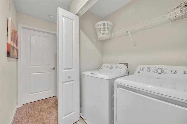 clothes washing area featuring light carpet and washer and dryer