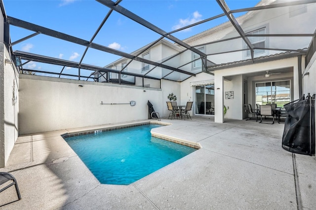 view of swimming pool featuring a patio, glass enclosure, and ceiling fan