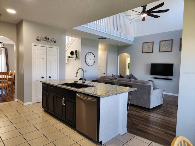 kitchen with sink, stainless steel dishwasher, ceiling fan, light wood-type flooring, and an island with sink