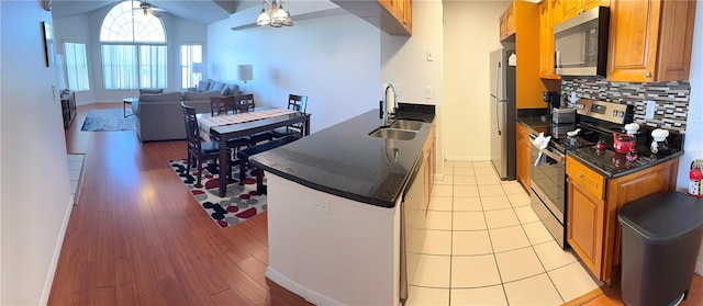 kitchen with sink, ceiling fan, light wood-type flooring, tasteful backsplash, and stainless steel appliances